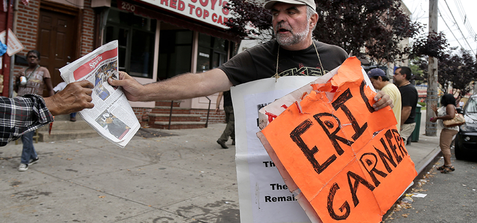 Doug Phaneuf hands a newspaper to a pedestrian while offering information to passers-by about a rally for Eric Garner, Friday, Aug. 1, 2014, in the Staten Island borough of New York. Garner died after he was put in a chokehold while being arrested last month for selling untaxed loose cigarettes. On Friday, the medical examiner ruled Garner's death to be a homicide caused by a police chokehold. (AP Photo/Julie Jacobson)
